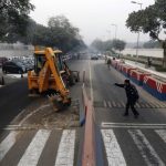 A traffic policeman guides a bulldozer removing the security barriers in front of the U.S. embassy in New Delhi