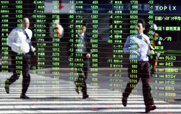 Pedestrians are reflected on a stock quotation board at a brokerage in Tokyo