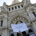 An anti-eviction activist holds an envelope in front of Madrid's Town Hall