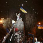 People climb up to the top of a pedestal after a statue of Soviet state founder Vladimir Lenin was toppled by protesters during a rally organized by supporters of EU integration in Kiev