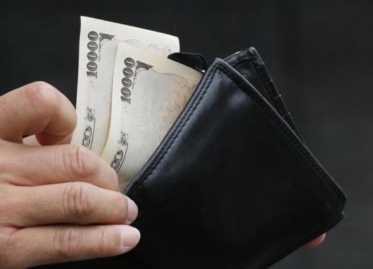 A man holds Japanese 10,000 Yen bank notes in front of a bank in Tokyo