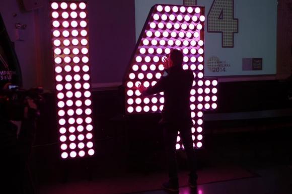 A man inspects the numbers "14" lit by Phillips LED lamps that will be installed atop One Times Square to complete the "2014" sign that lights up at midnight on New Year's Eve announcing the beginning of the new year during a news conference in New York