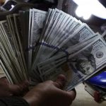A money changer inspects U.S. dollar bills at a currency exchange in Manila