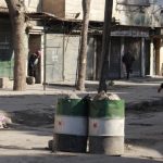 A Free Syrian Army fighter guides a civilian who is crossing a street in Aleppo