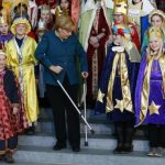German Chancellor Merkel stands with aid of crutches as she meets carols singers during reception at Chancellery in Berlin