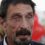 Computer software pioneer McAfee speaks with reporters outside his hotel in Miami Beach