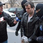 Lehel, alleged hacker "Guccifer", is escorted by masked policemen in Bucharest, after being arrested in Arad