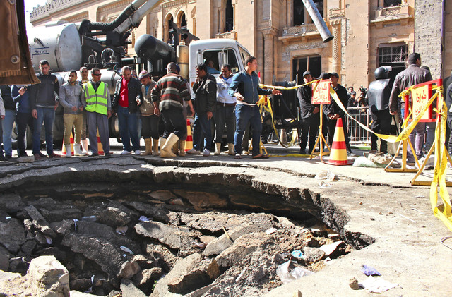 Police officers secure a crater left in front of Cairo's police directorate after an explosion