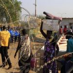 Displaced people walk past razor wire at Tomping camp, where some 15,000 displaced people who fled their homes are sheltered by the United Nations, near Juba