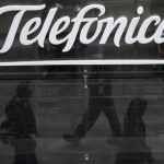 People are reflected as they walk past Spanish telecom group Telefonica's flagship store in central Madrid