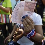 A woman holds money to donate to protest leader Suthep Thaugsuban as he leads thousands of anti-government demonstrators marching in Bangkok