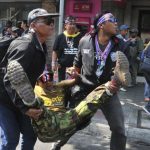 Anti-government protesters carry a fellow protester injured in a grenade attack during a rally in Bangkok
