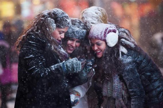 Tourists look at a camera in snowstorm in Times Square, Midtown, New York