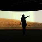 Jacqueline Storey, a press officer at the National Maritime Museum, poses for a photograph in front of images of Mars generated by NASA's Curiosity Rover at their new Visions of the Universe exhibition, in Greenwich, London