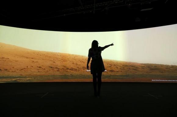 Jacqueline Storey, a press officer at the National Maritime Museum, poses for a photograph in front of images of Mars generated by NASA's Curiosity Rover at their new Visions of the Universe exhibition, in Greenwich, London