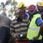 A suspected illegal miner talks to officials after being rescued from an abandoned gold shaft in Benoni