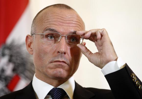 Defence Minister Klug adjusts his glasses during a news conference in Vienna