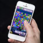 A woman poses for a photo illustration with an iPhone as she plays Candy Crush in New York