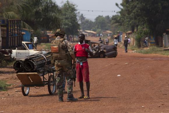 A French peacekeeping soldier searches a man for weapons in the district of Miskine of the capital Bangui