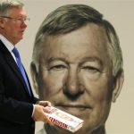 Former Manchester United manager Alex Ferguson poses with his new autobiography before a book signing at a supermarket in Manchester