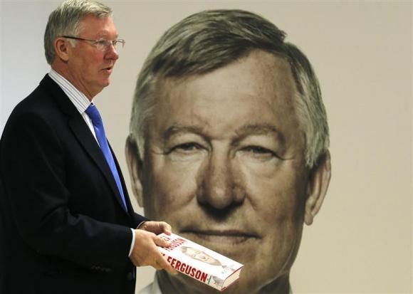 Former Manchester United manager Alex Ferguson poses with his new autobiography before a book signing at a supermarket in Manchester