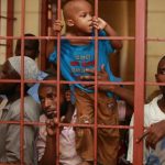 A boy, who was with fellow Muslims detained by police from Sunday's raid at the Masjid Mussa mosque, climb in a cell as the men wait to be arraigned at a court in Shanzu