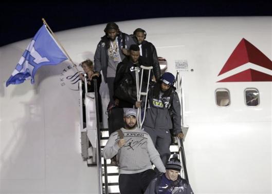Seahawks' Sherman carries his crutches as he exits the team's chartered flight home after winning NFL Super Bowl XLVIII in Seattle