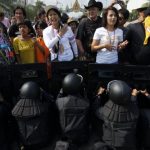 Anti-government protesters confront riot police at one of the barricades near the Government House in central Bangkok