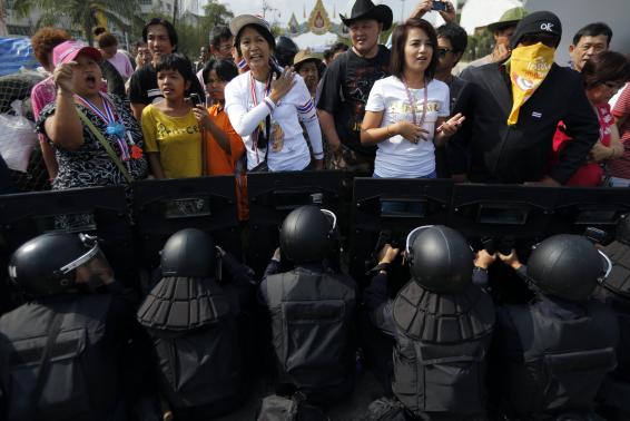 Anti-government protesters confront riot police at one of the barricades near the Government House in central Bangkok