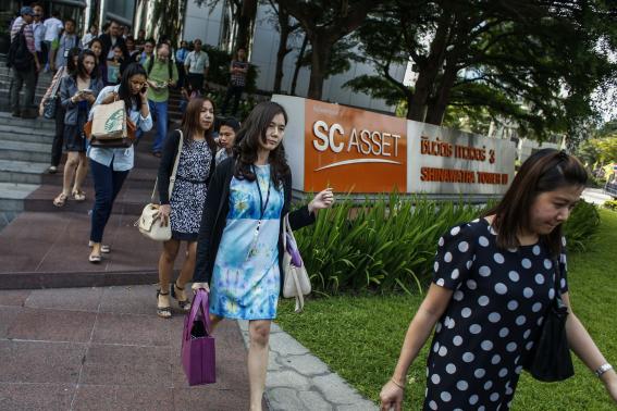 Workers leave a business building owned by SC Asset Corp as anti-government protesters gather outside during a rally in Bangkok