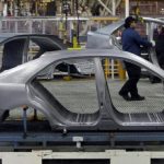 An Auto worker loads bodyshells of a Toyota Camry Hybrid car onto the assembly line at the Toyota plant in Melbourne