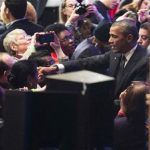 U.S. President Barack Obama is reflected in a mirror as he shakes hands with activists in Washington