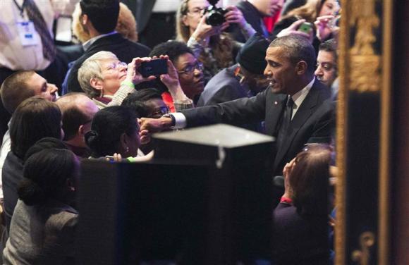 U.S. President Barack Obama is reflected in a mirror as he shakes hands with activists in Washington