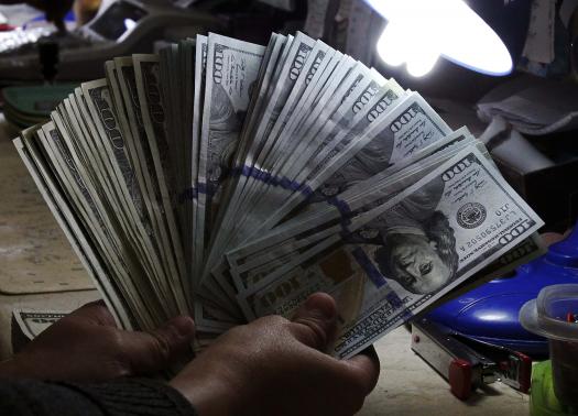 A money changer inspects U.S. dollar bills at a currency exchange in Manila