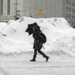 A woman uses an umbrella to shelter from snow flurries in Manhattan