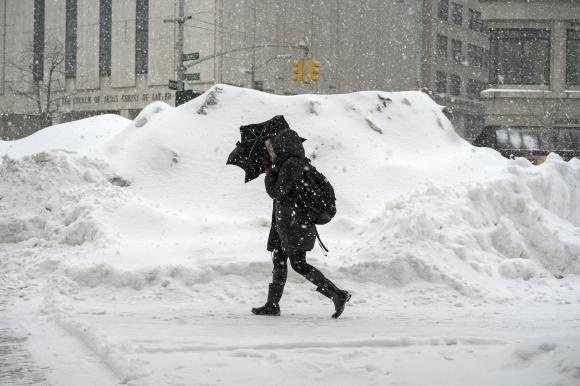 A woman uses an umbrella to shelter from snow flurries in Manhattan