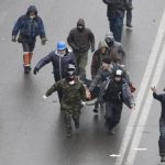 Anti-government protesters run with an injured man on a stretcher in Independence Square in Kiev