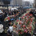 People surround a makeshift memorial as they gather to commemorate the victims of the recent clashes in central Kiev