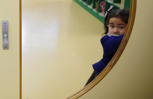 A girl opens the door of a teacher's staff room at the Emporium kindergarten in Koriyama, west of the tsunami-crippled Fukushima Daiichi nuclear power plant, Fukushima prefecture