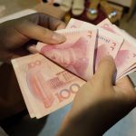 A woman counts Chinese yuan notes at a market in Beijing