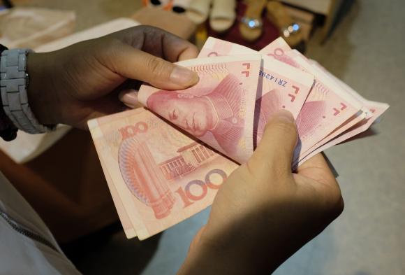 A woman counts Chinese yuan notes at a market in Beijing