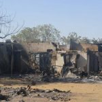 A woman walks past homes destroyed by Boko Haram militants in Bama