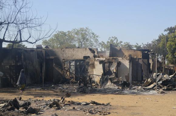 A woman walks past homes destroyed by Boko Haram militants in Bama