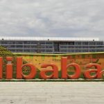 A worker walks past a logo of Alibaba Group at its headquarters on the outskirts of Hangzhou