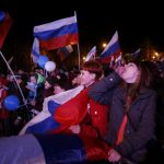 People celebrate and wave Russian flags as the preliminary results of today's referendum are announced in the Crimean city of Sevastopol