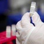 A manufacturing associate holds a vial with a DCVax-L label in a Northwest Biotherapeutics laboratory in Memphis