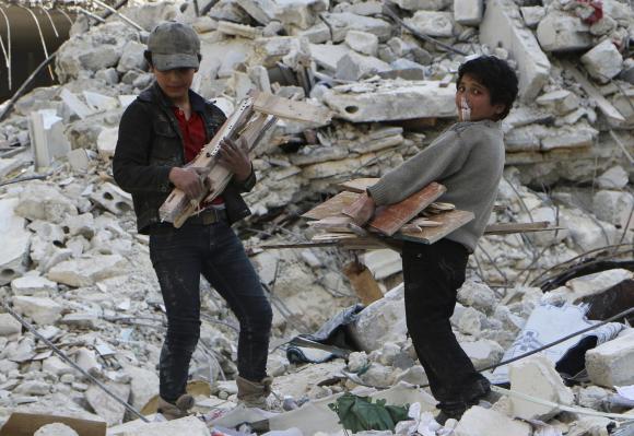 A child blows a bubble gum while collecting firewood amid damage and debris after what activists said was an air strike by forces loyal to Syria's President Bashar al-Assad in the Al-Maysar neighbourhood of Aleppo