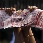 Anti-government protesters hold Thai baht banknotes during a march in central Bangkok