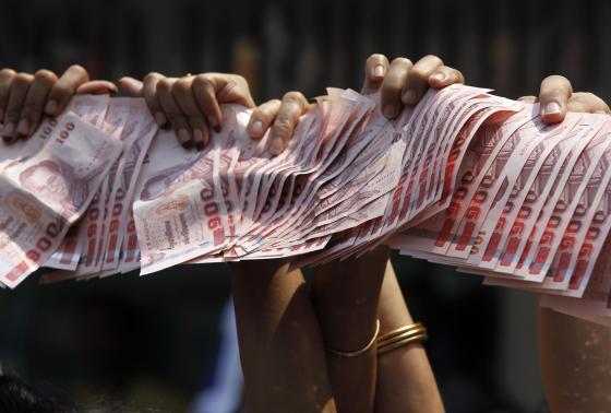 Anti-government protesters hold Thai baht banknotes during a march in central Bangkok