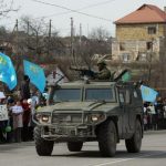 Pro-Ukrainian demonstrators react as an armoured military vehicle, believed to be Russian, passes by outside the Crimean city of Simferopol